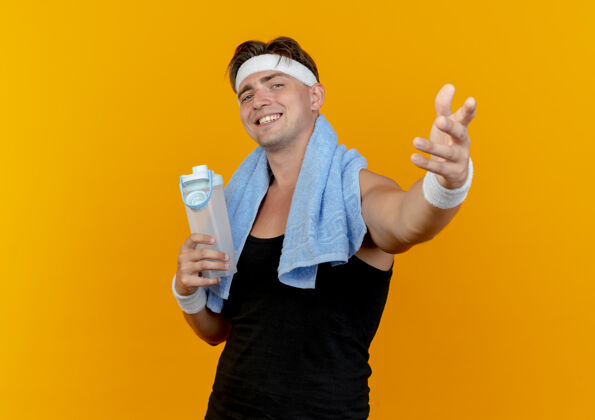 人面带微笑的年轻帅气的运动型男人戴着头带和手腕拿着水瓶隔离在橙色的墙上人微笑运动