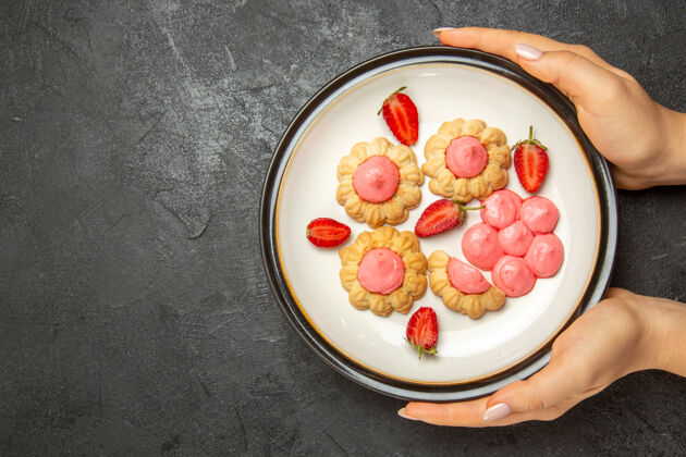 早餐顶视图美味的小饼干与粉红色奶油内板在灰色的表面营养品桌子饼干