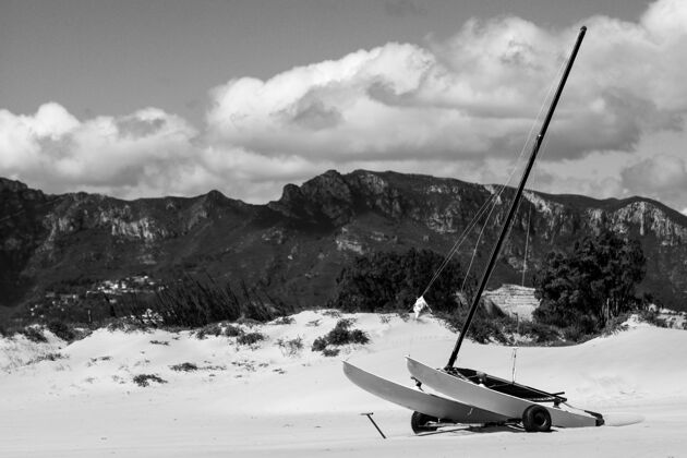 旅行雪山上一只风帆独木舟在轮子上的灰度照片雪灰度航行