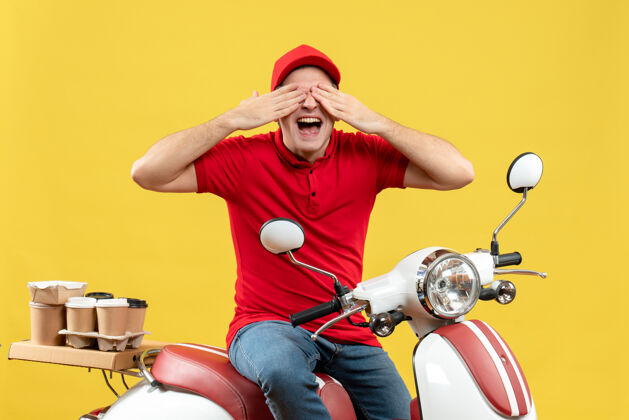 眼睛上图是穿着红色上衣戴着帽子的快乐的年轻人坐在踏板车上 在黄色的背景上闭上眼睛传递命令摩托车背景成人