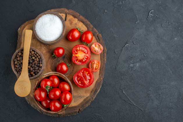 食品全切新鲜番茄和胡椒在木板上黑色表面俯视图可食用水果樱桃胡椒