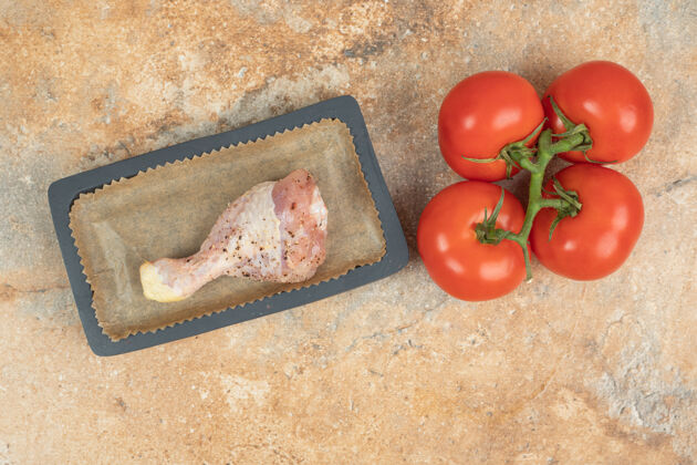 肉用生鸡腿和西红柿做的深色板蔬菜鸡腿美味