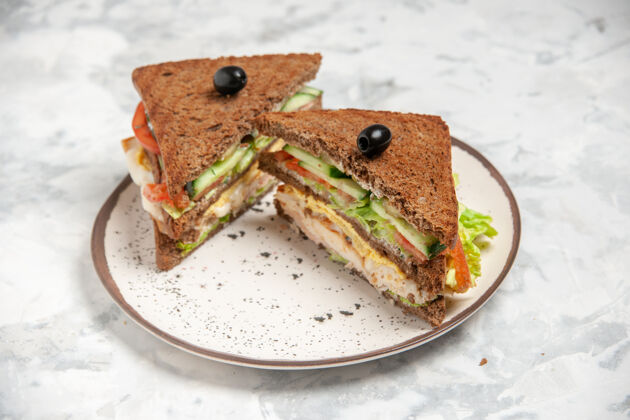 美味美味三明治的俯视图 黑色面包上点缀着橄榄 盘子上有白色的污渍美食食物肉