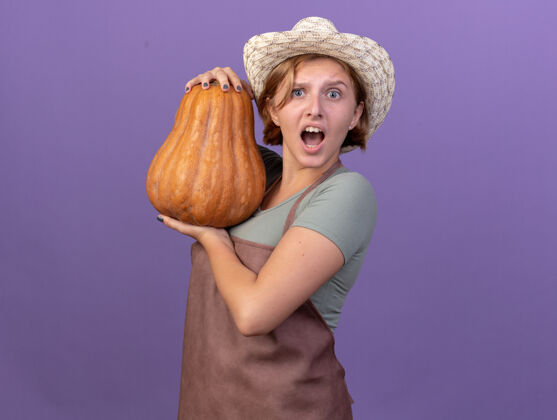 焦虑焦虑的年轻斯拉夫女园丁戴着园艺帽 手里拿着紫色的南瓜花园年轻帽子
