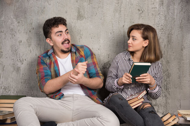 阅读一对年轻夫妇坐在一起 互相拿着一本书情侣坐着学习