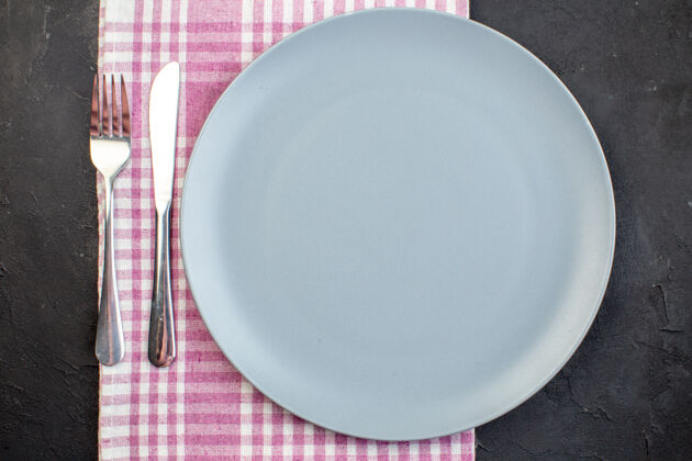 桌子顶视图蓝色板与刀叉在黑暗的表面刀深色叉子