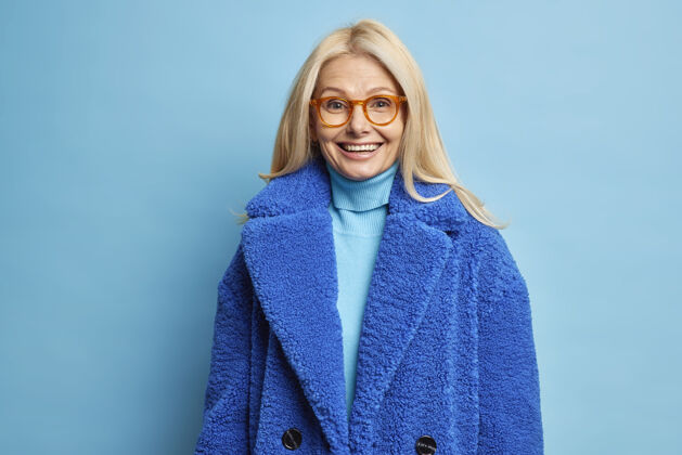 外套冬季时尚概念快乐微笑的中年金发女人戴着眼镜和蓝色外套中等高兴时尚