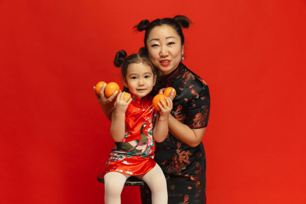 旗袍拥抱 微笑 抱着乡巴佬2020年中国新年快乐传统服装红色背景上的亚洲母女肖像庆祝 人类情感 节日复制空间灯笼情感新年