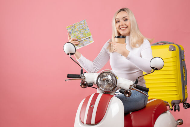 坐着正面图：骑着轻便摩托车的快乐小姐 带着黄色手提箱指着地图微笑轻便摩托车成人