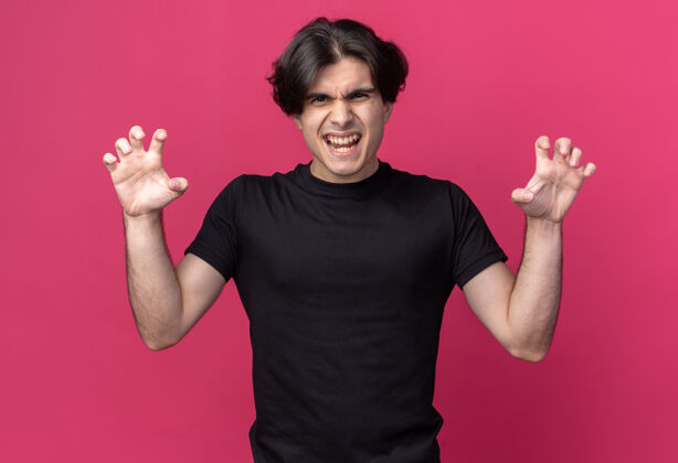 穿着快乐的年轻帅哥穿着黑色t恤做老虎式的手势孤立在粉红色的墙上人表情脸