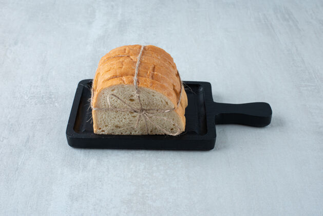 小麦白面包用绳子绑在黑木板上木头美味切片