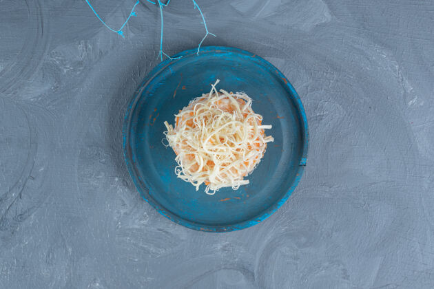 米饭在一个蓝色的盘子里 在大理石桌上装饰性的树枝旁边 盛上煮熟的米饭奶酪可口烹饪