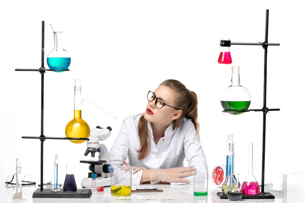 人前视图穿着医疗服的女化学家坐在白色背景上 用不同的溶液化学大流行健康covid女化学家健康不同