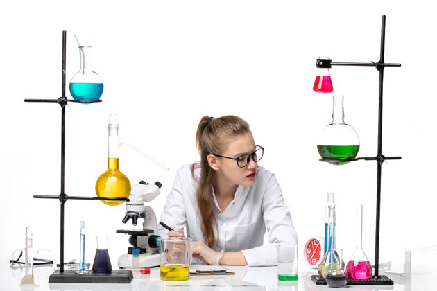 健康前视图穿着医疗服的女化学家在白色背景上写笔记化学大流行健康病毒实验室套装观点