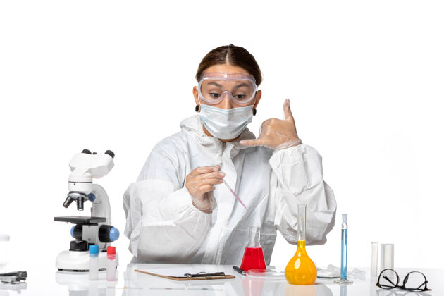 前台正面图：穿着防护服 戴着口罩的女医生正在用白色办公桌上的病毒冠状病毒解决方案工作医院实验室外套医疗