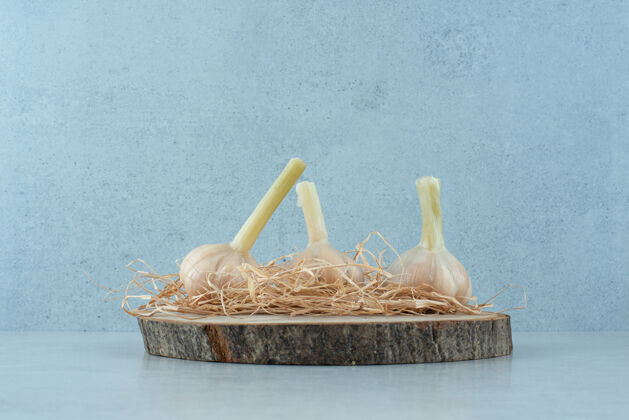 生的三个生蒜放在木片上蔬菜熟的木材
