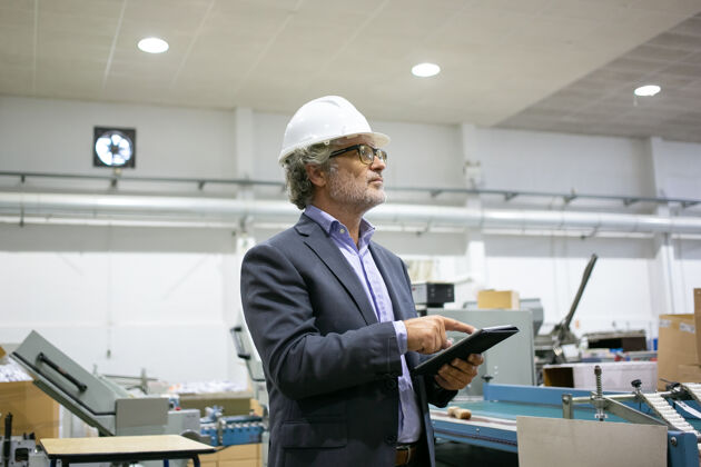 老板认真的主管在白盔上拿着平板电脑 看着生产过程西装工厂内容