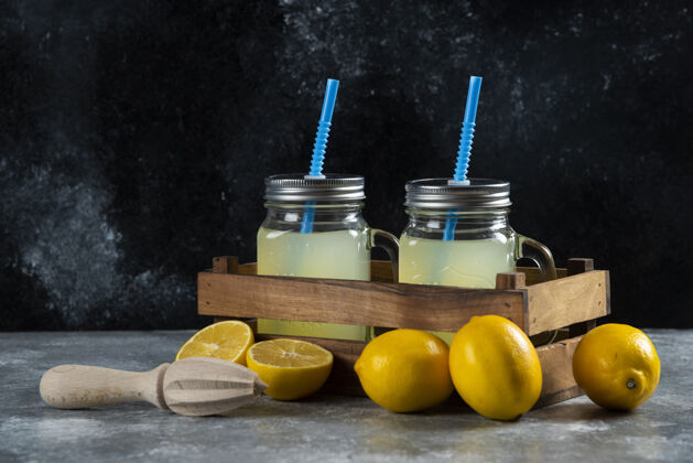 罐子两个装着稻草和切片的柠檬汁的玻璃罐放在木篮里水果美味提神