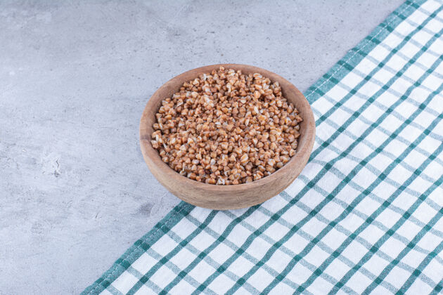 营养把一小碗荞麦放在铺在大理石表面的毛巾上配料谷类荞麦