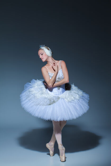 表演芭蕾舞演员在蓝色背景下扮演白天鹅的肖像舞蹈服装灵活
