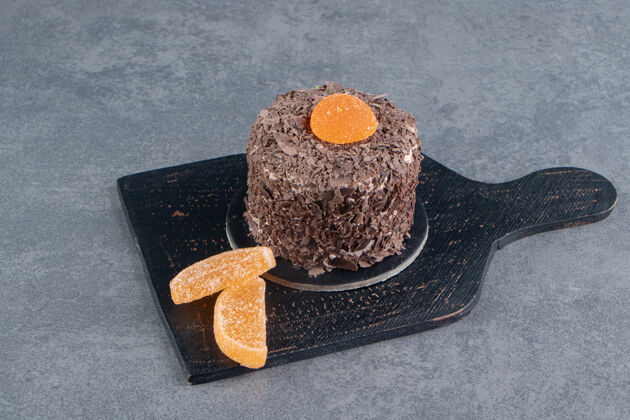 蛋糕黑木板上放着橘子果冻糖的巧克力蛋糕美味曲奇甜点