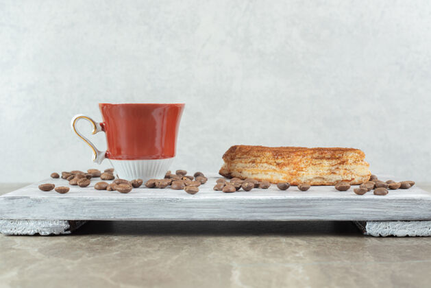 马克杯一杯咖啡豆和糕点放在木板上烤香味