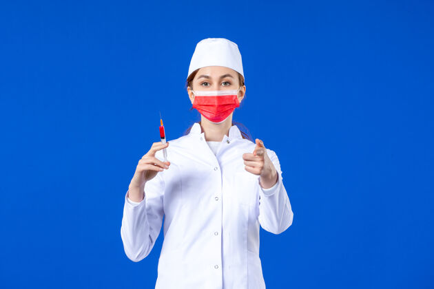 男人正面图：身穿白色医疗服的女护士 戴着红色面罩 手上拿着蓝色针剂医院流行病手