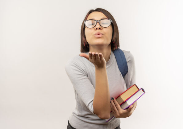 包年轻的女学生戴着眼镜 背着书包 对着镜头吹吻 背景是白色的 还有复印空间吹送吻