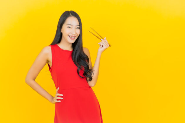 年轻人在黄色的墙上画一幅美丽的亚洲年轻女子拿着筷子准备吃饭饭女孩女人