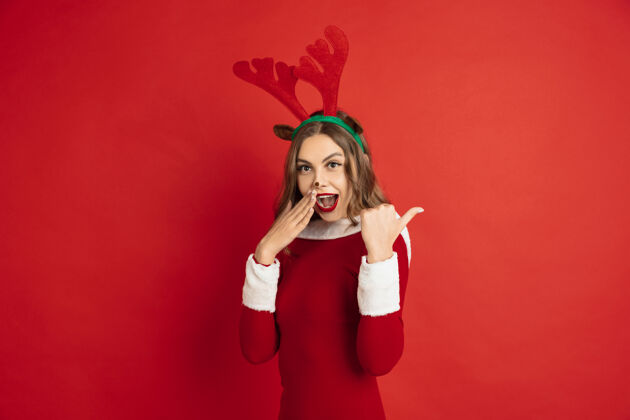 圣诞节美丽的女人像圣诞鹿隔离在红墙的概念尼古拉斯情感积极