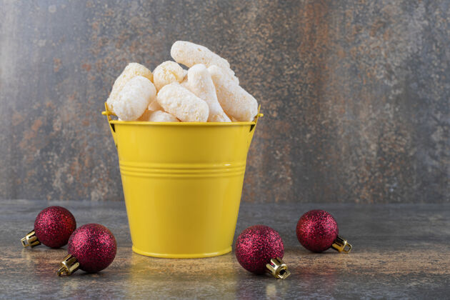 美味玉米零食堆在一个桶旁边的圣诞饰品大理石表面圣诞饰品玉米垃圾食品