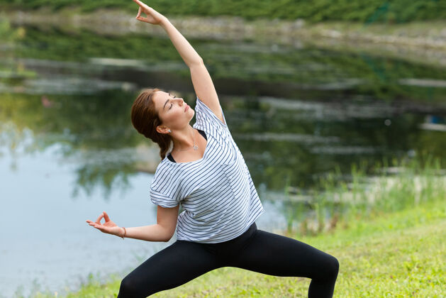 集中年轻漂亮的女人在绿色公园做瑜伽练习姿势早晨冥想