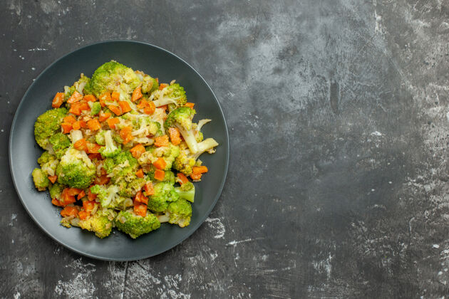 健康上图：灰色桌子上黑色盘子上放着西兰花和胡萝卜的健康餐食品午餐炊具