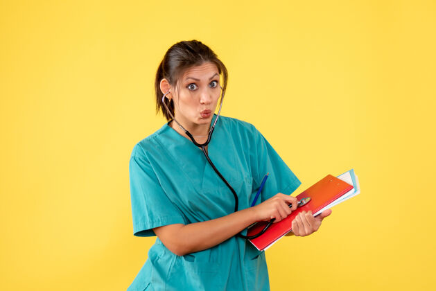 人前视图穿着医用衬衫的女医生 黄色背景上有听诊器和注释女医生笔记黄色