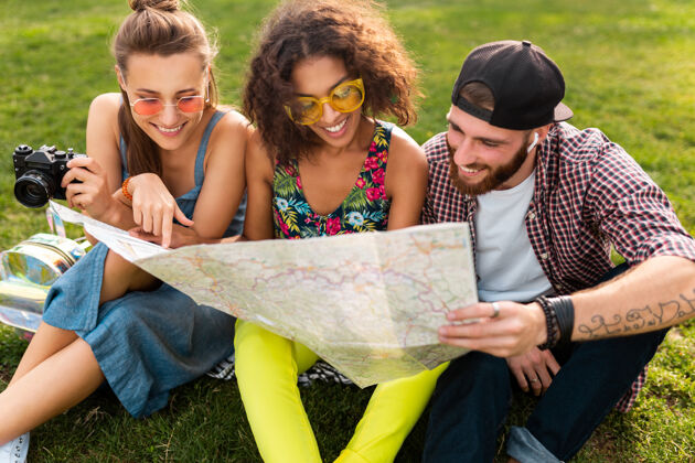 团体快乐年轻的朋友们一起坐公园旅游 看地图观光 男女同乐友谊地图旅游