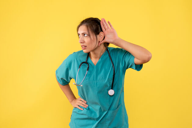 衬衫前视图穿着医用衬衫的女医生在黄色背景上聆听视图专业人