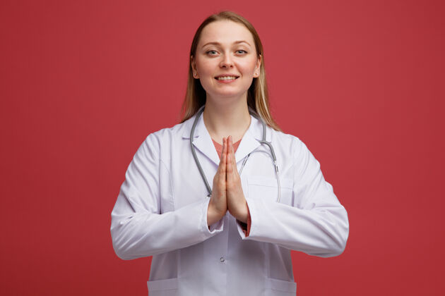 长袍微笑着的年轻金发女医生 穿着医用长袍 脖子上戴着听诊器 做着一个非常棒的手势医生听诊器年轻