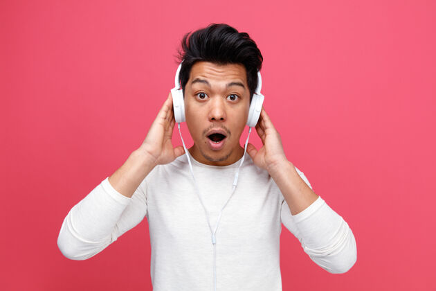 男人惊讶的年轻人戴着耳机 手放在他们身上听音乐音乐耳机粉色
