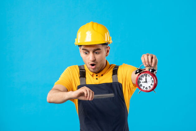 建筑商穿着制服的男工人的正视图 蓝色的时钟很晚承包商时钟头盔