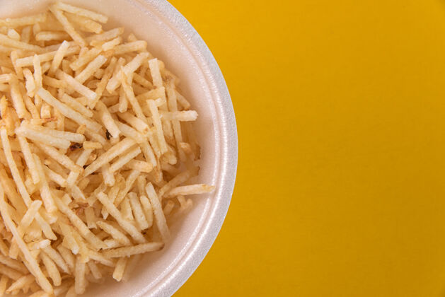 美味白色的碗 黄色的背景上有土豆杆食物传统土豆薯条