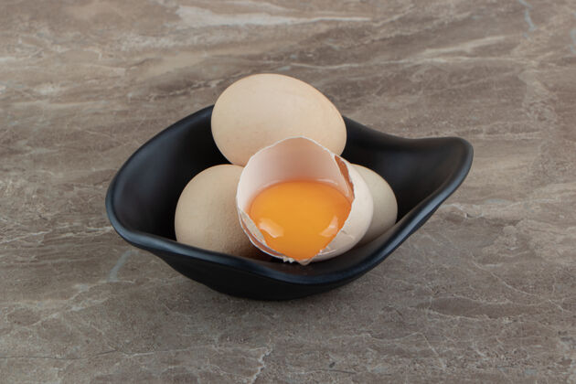 蛋壳黑碗里的生鸡蛋生的裂纹鸡肉
