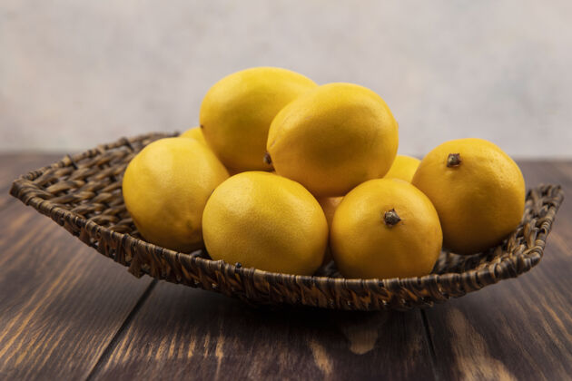 健康侧视图新鲜的黄色柠檬柳条托盘上的木制表面美味厨房壁板