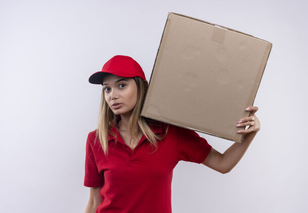 持有年轻的送货员穿着红色制服 戴着帽子 肩上扛着一个大箱子交货大年轻