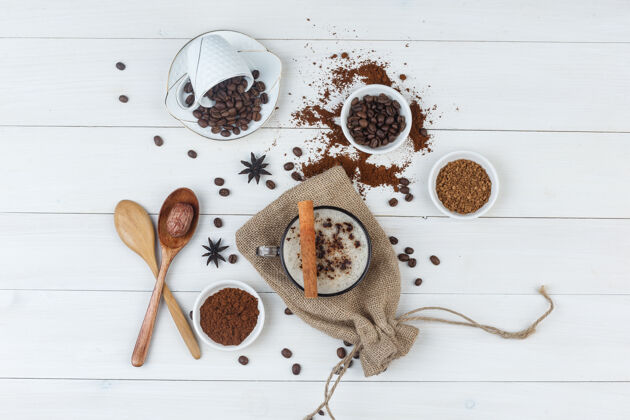 拿铁一套咖啡豆 磨碎的咖啡 香料 木勺和咖啡在一个木杯和麻袋背景顶视图咖啡馆摩卡咖啡早餐