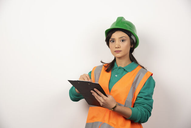 肖像严肃的女工业工程师 穿着制服 白色背景上有剪贴板建筑工程师工作