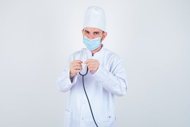 公司帅哥穿着白色的医学实验服 戴着口罩 手持听诊器 看上去很自信 正面照英俊外套站
