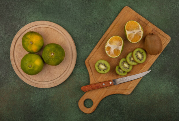 猕猴桃顶视图猕猴桃切片用刀在砧板上与橘子站在一个绿色的墙壁刀切顶部