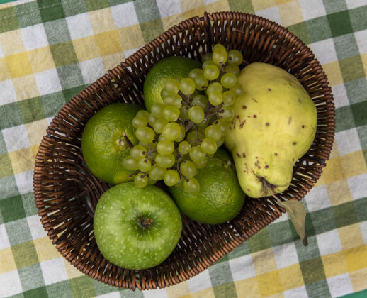 上衣顶视图绿色的葡萄和绿色的苹果 橘子和梨在一个绿色的黄色格子毛巾篮子葡萄水果橘子