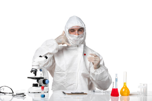 医生正面图：男医生穿着防护服 戴着口罩 因为白色桌子上有一个小瓶子病毒药品面罩