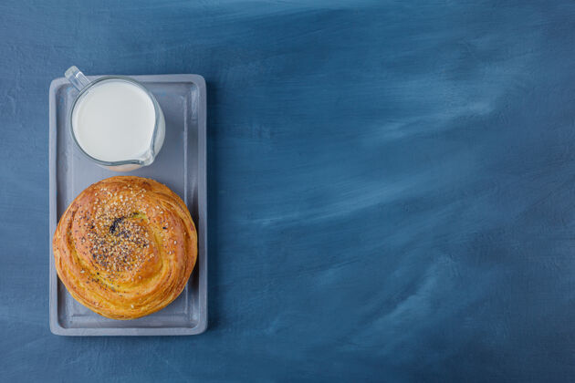 食品一盘美味的黑籽糕点和一杯牛奶放在蓝色的表面上早餐甜点曲奇